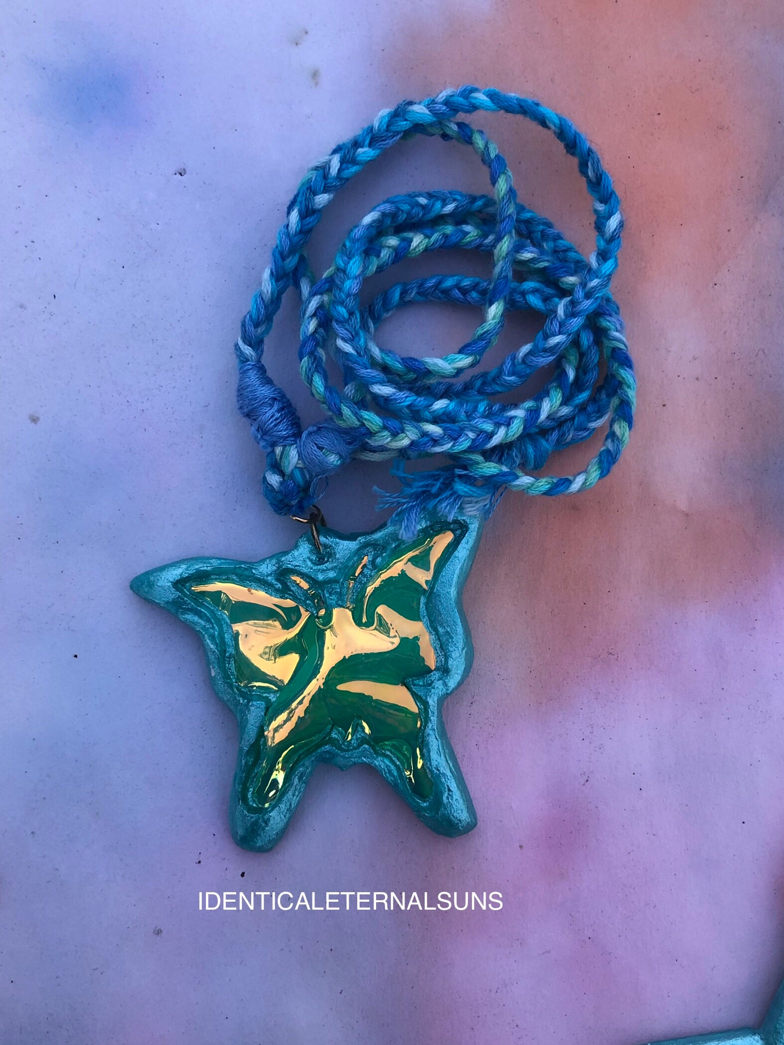 Star-shaped pendant with blue braided cord on a light pink background